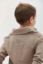 Back of a child wearing the Kids' Tetra Set - Mocha, showing an embroidered eye design and text on the back of the shirt