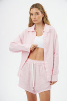 Woman wearing a pink and white striped Pure Linen Women's Button-Up Shirt and matching shorts