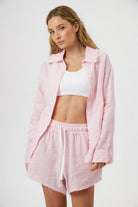 Woman wearing a pink textured shirt and shorts set on a white background
