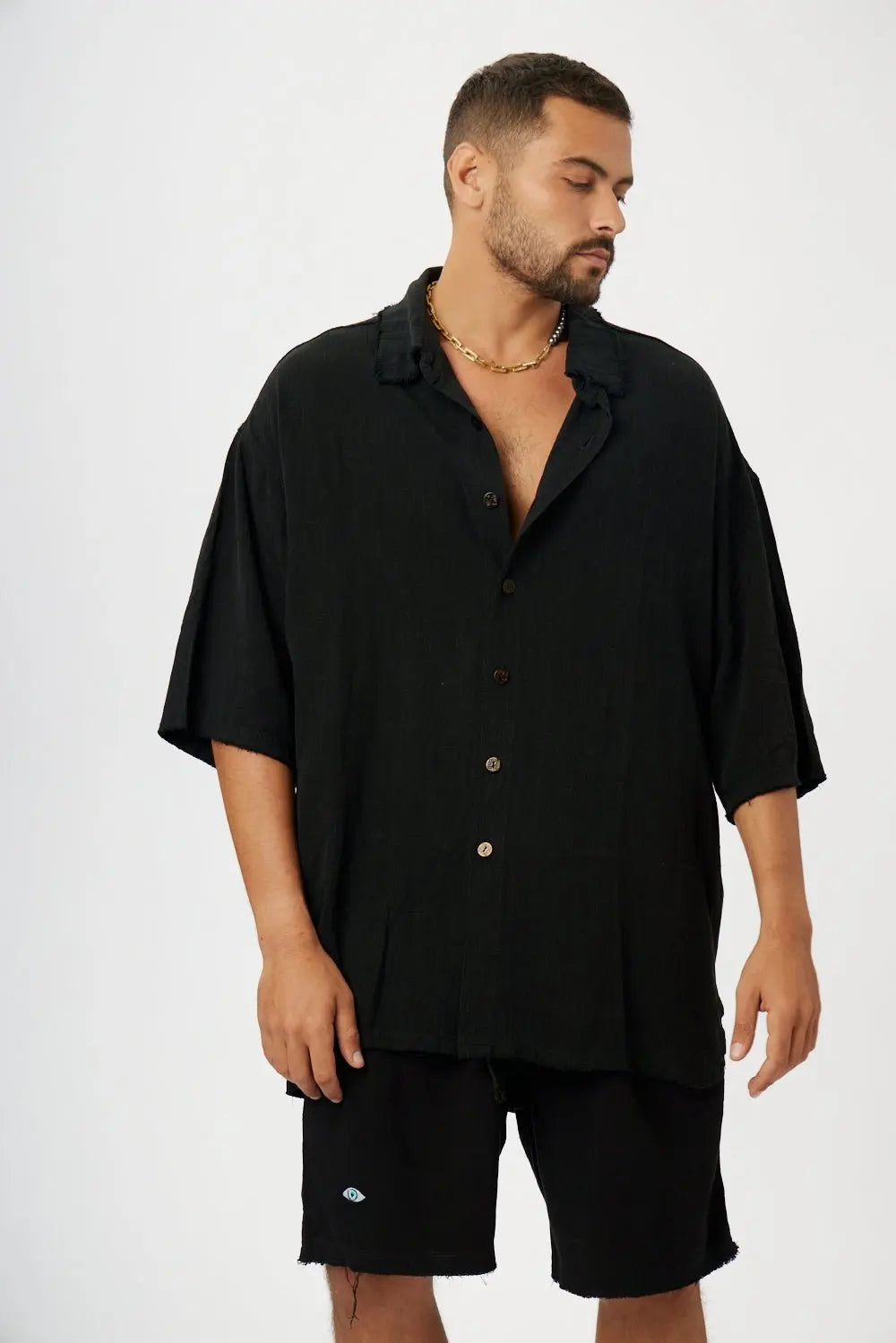 Man wearing a black soft linen short sleeve button-up shirt and black shorts