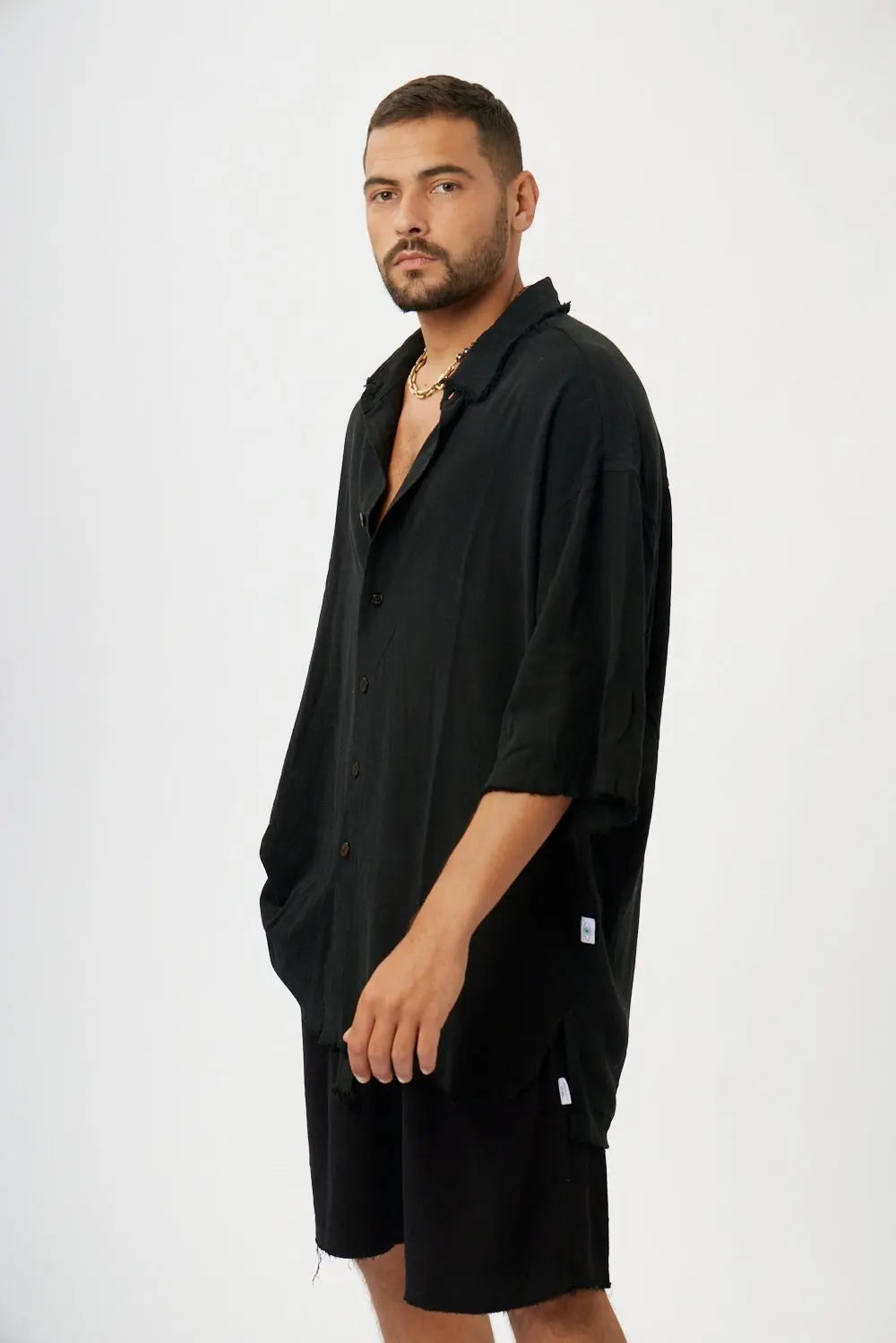 Man wearing a black soft linen short sleeve button-up shirt and black shorts