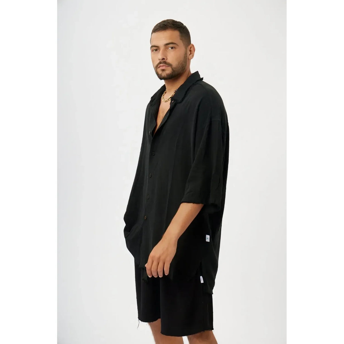 Man wearing a black soft linen short sleeve button-up shirt and black shorts