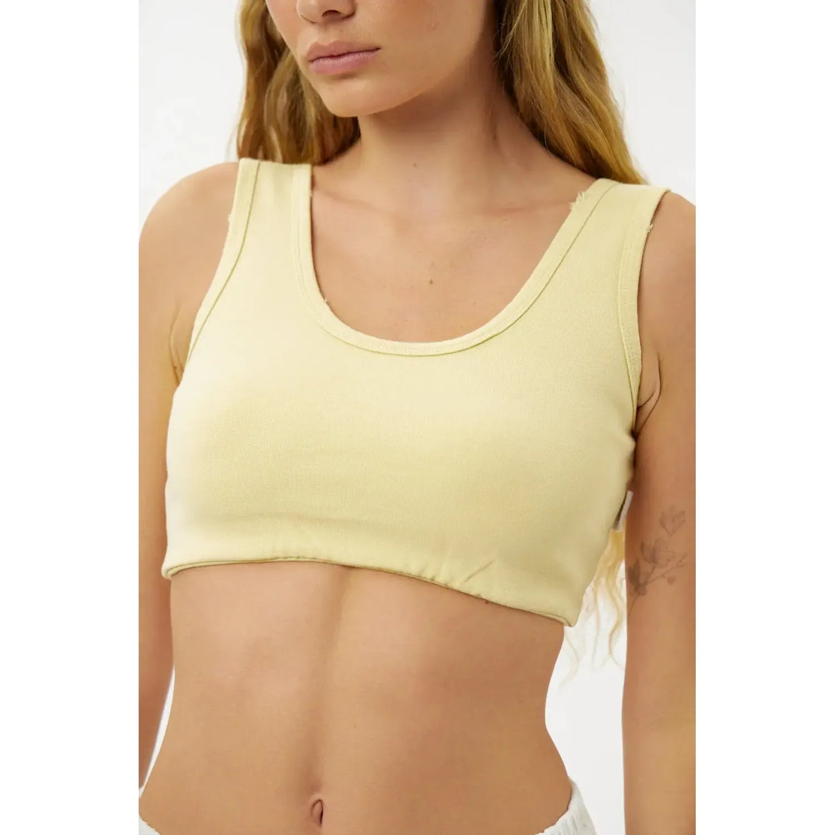 Woman wearing a light yellow tank top against a white background