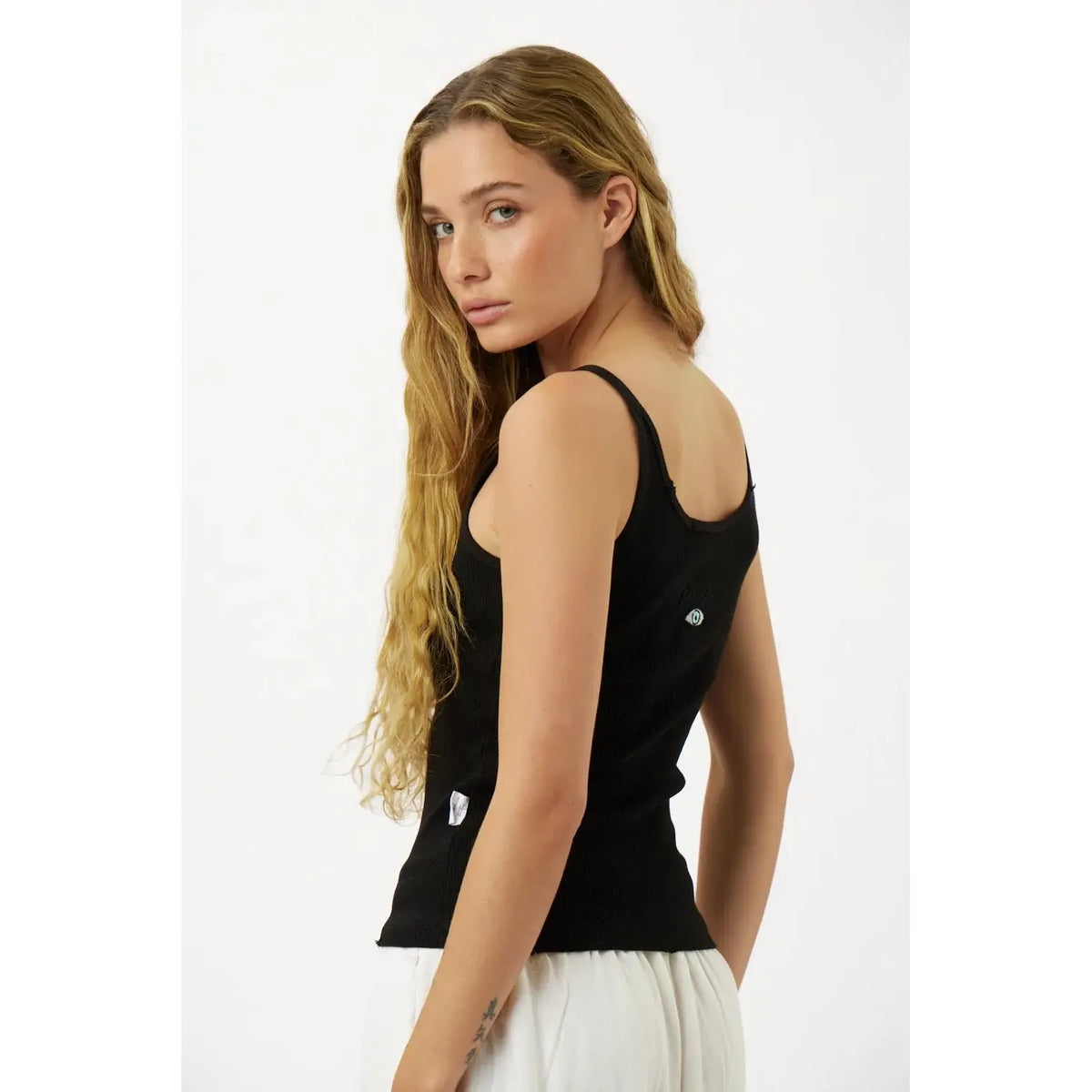 Slim Cotton Tank Top in black, worn by a woman with long blonde hair, looking over her shoulder