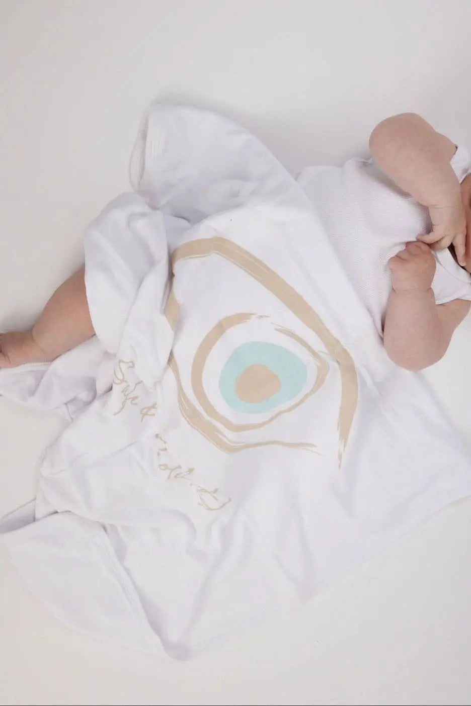 Baby covered by a white Cotton Single Elliptical Eye Blanket with a large eye graphic
