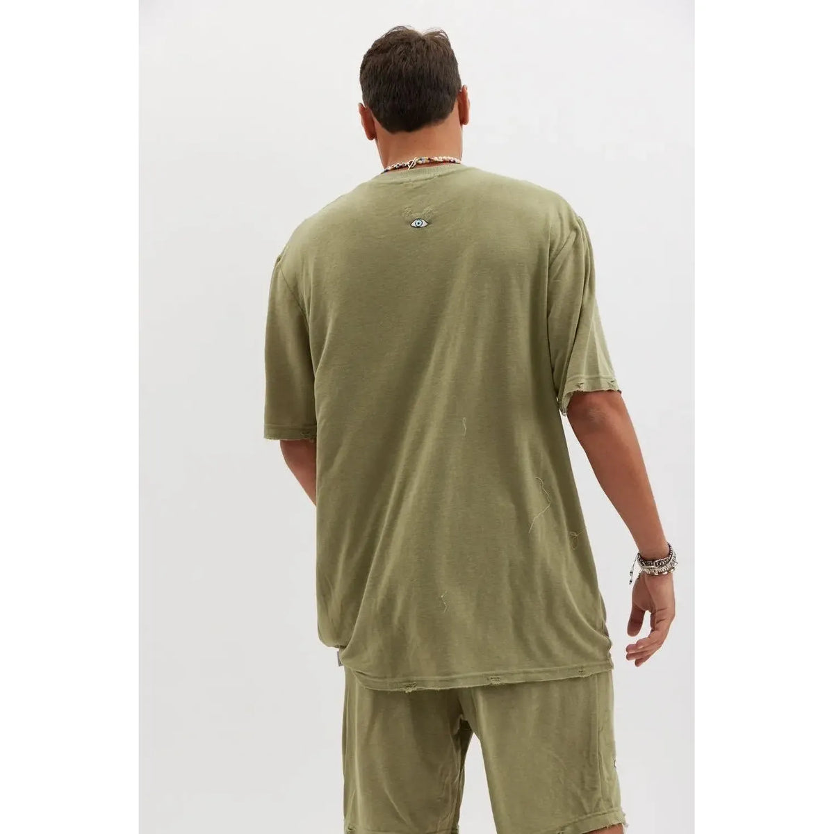 Back of a person wearing an olive TFU Soft Essential Tee and matching shorts, with a small eye graphic on the upper back of the tee