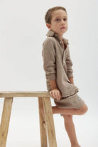 Kids' Tetra Set - Mocha. A young boy in a mocha-colored textured shirt and shorts sits on a wooden stool