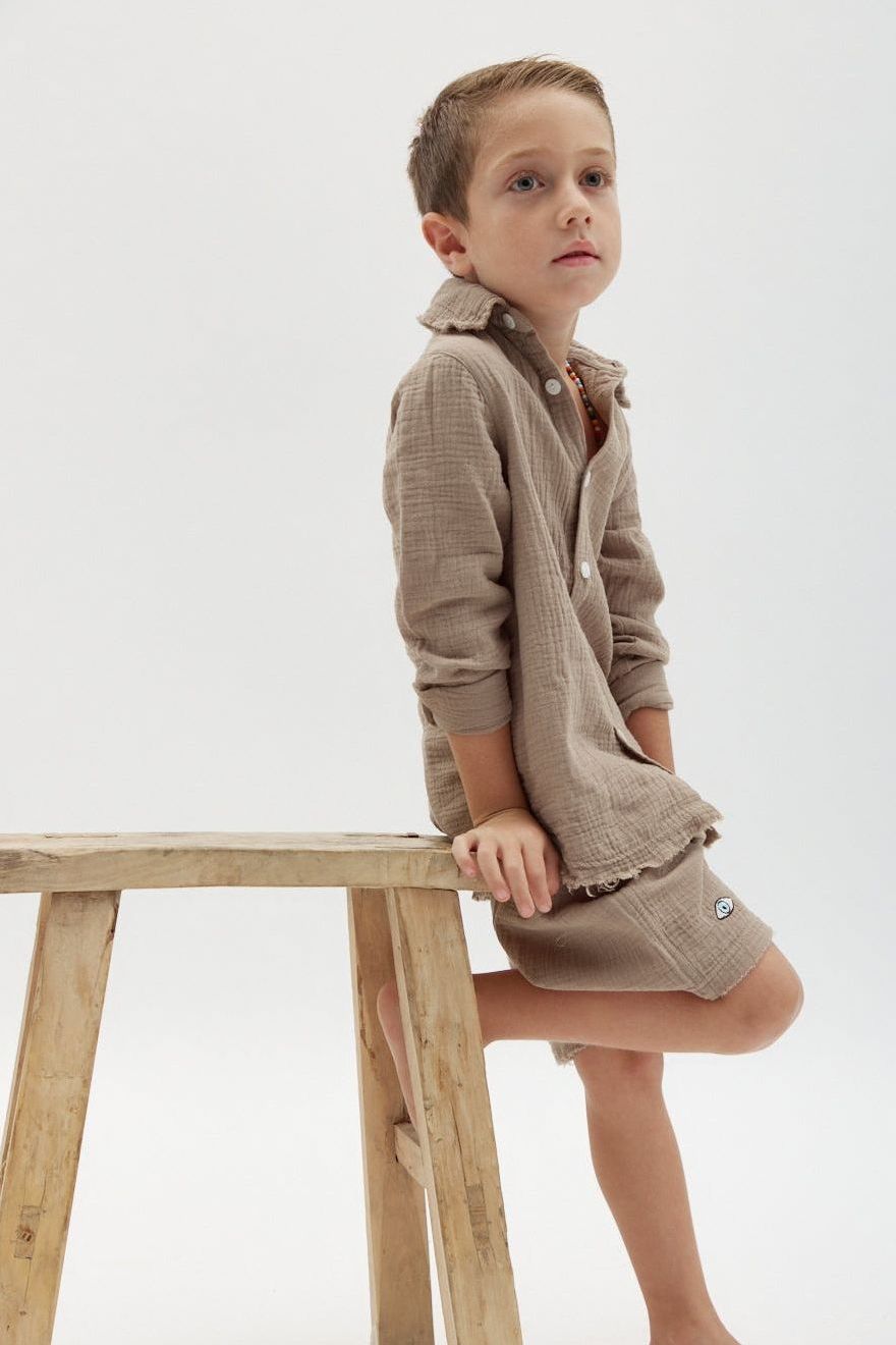 Kids' Tetra Set - Mocha. A young boy in a mocha-colored textured shirt and shorts sits on a wooden stool