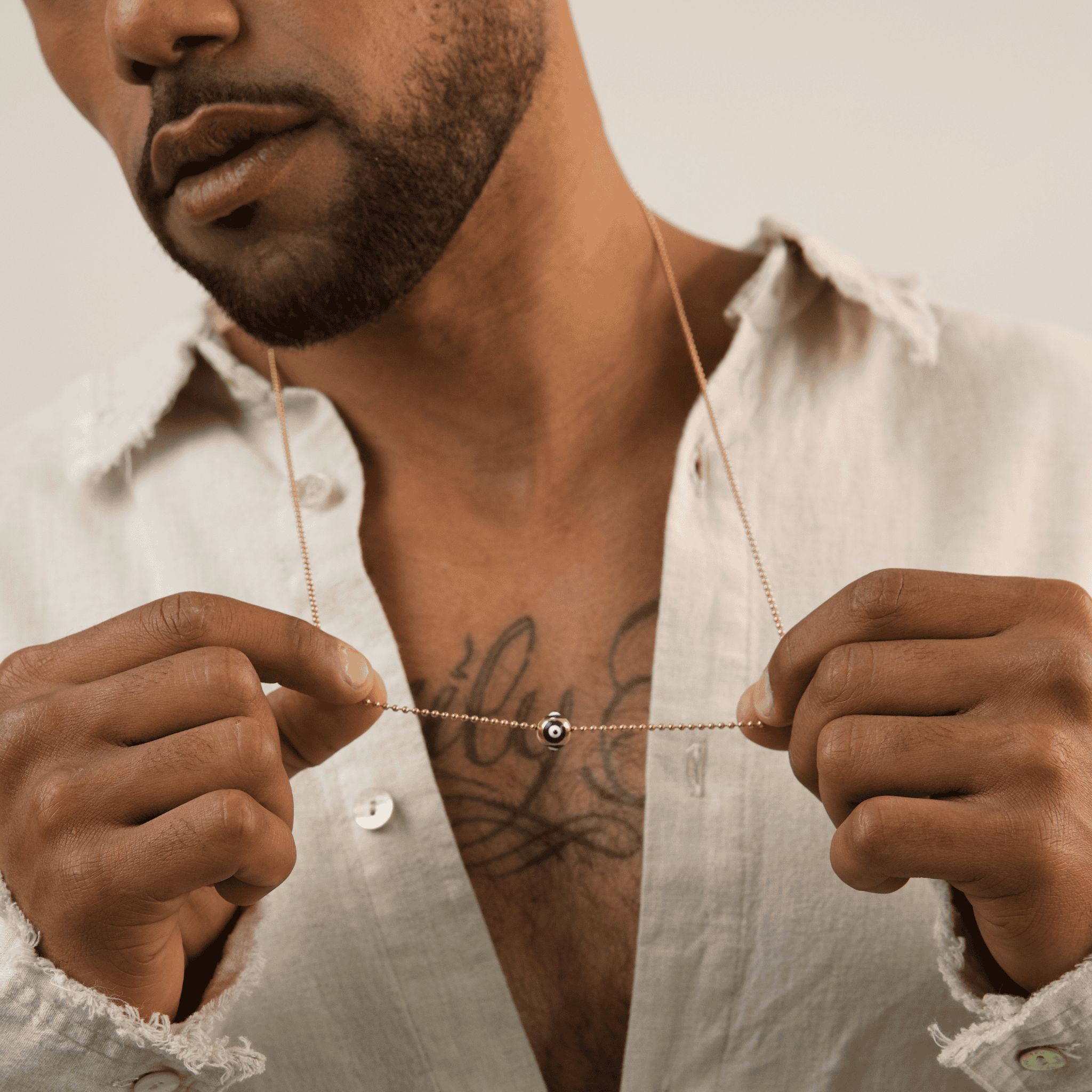 Man holding a delicate necklace with a small pendant