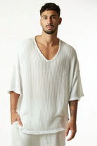 Man wearing a cream white striped knit shirt with a v-neck and short sleeves